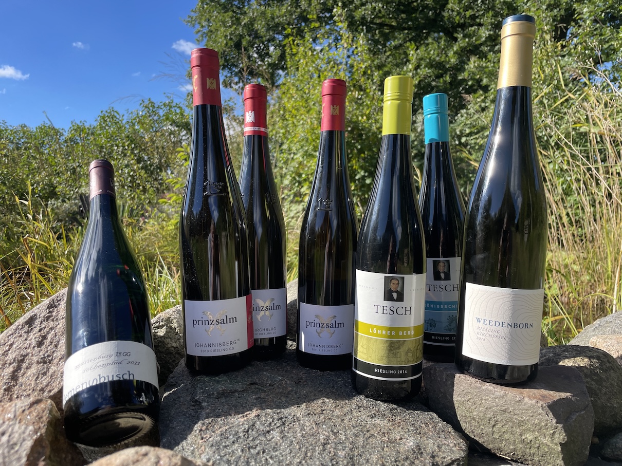 Verschiedene Weinflaschen sind auf Steinen und Findlingen aufgestellt.