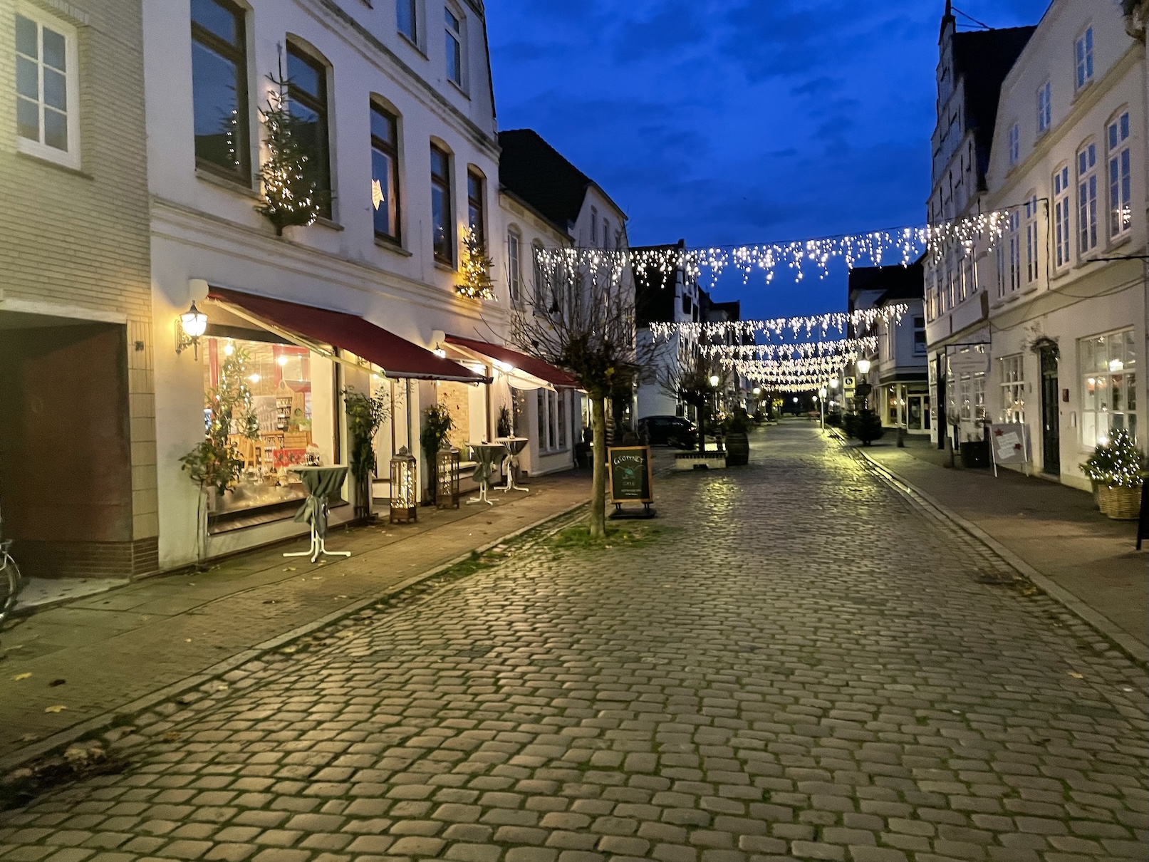 Die Friedrichstädter Fußgängerzone während der Dämmerung mit Lichterketten zwischen den Gebäuden.