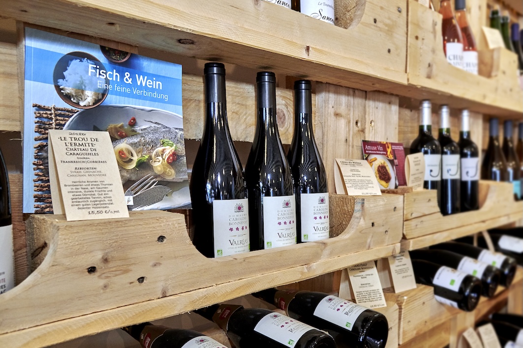 Ein Auschnitt eines Weinregals mit Informationen zu den Weinen.